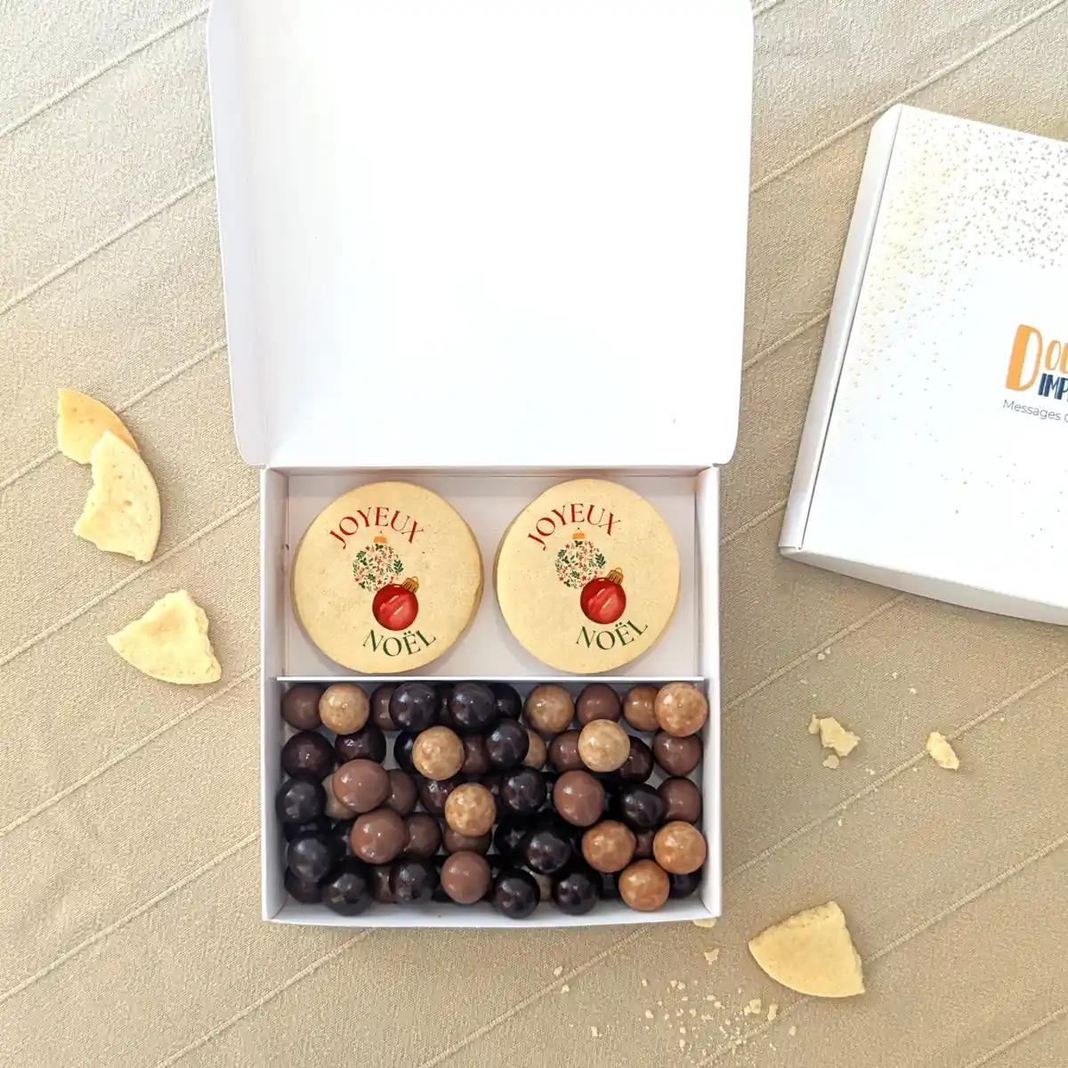 Coffret de Noël avec biscuits “Merry Christmas” et chocolats assortis dans une boîte blanche festive.